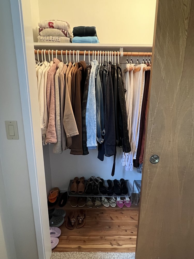 Organized bedroom closet with neatly hung clothes and shoes arranged systematically