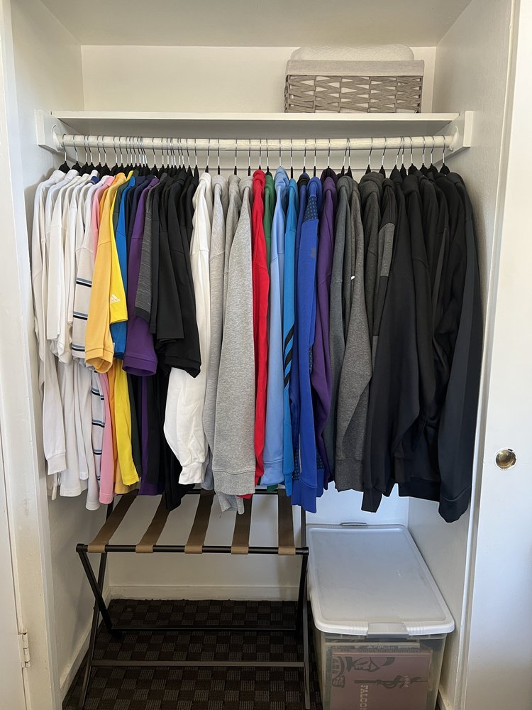 Organized reach-in bedroom closet with systematic clothing arrangement and clear storage solutions