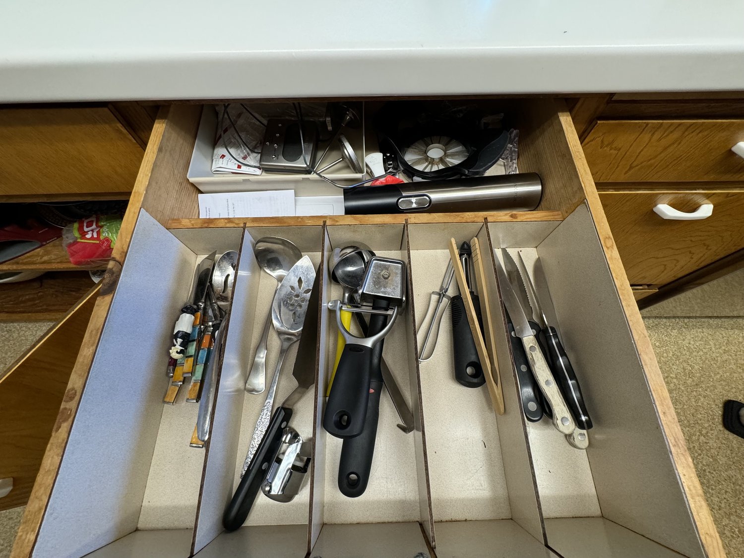 Chaotic kitchen drawer with utensils, gadgets, and tools jumbled together in a tangled mess