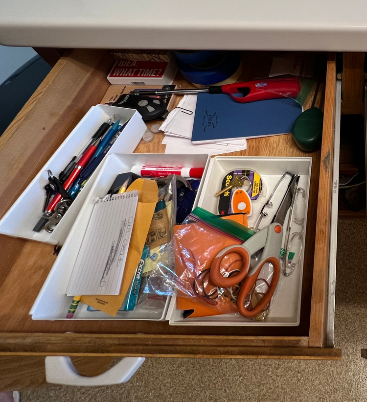 Messy kitchen junk drawer with batteries, twist ties, rubber bands, and miscellaneous items creating clutter